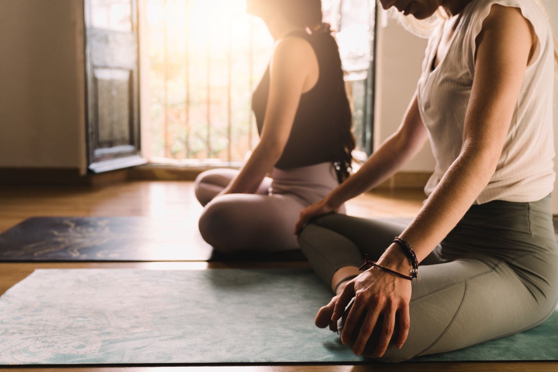 Junge Menschen in Meditationshaltung zu Hause bei Sonnenuntergang - Konzept für Achtsamkeit, Yoga und Bewegung