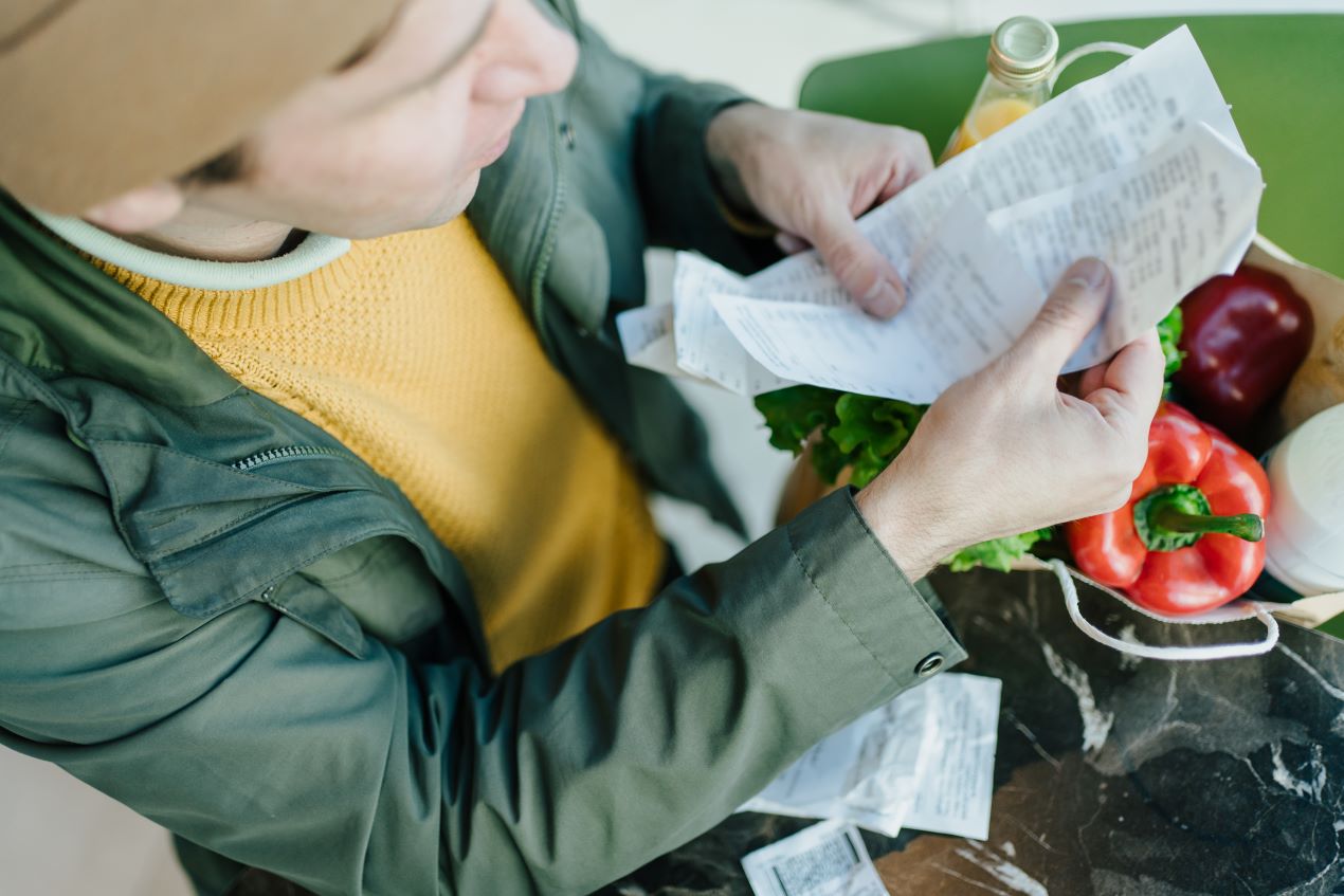 Mann überprüft eine Einkaufsliste mit frischen Lebensmitteln in einer Papiertüte – nachhaltiger Konsum und die Nutzung von Co2 Kapseln helfen, Geld zu sparen und umweltfreundlicher zu leben.