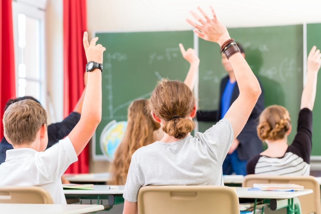 Schüler im privaten Gymnasium Berlin heben die Hand während des Unterrichts – kleine Klassen und individuelle Förderung.