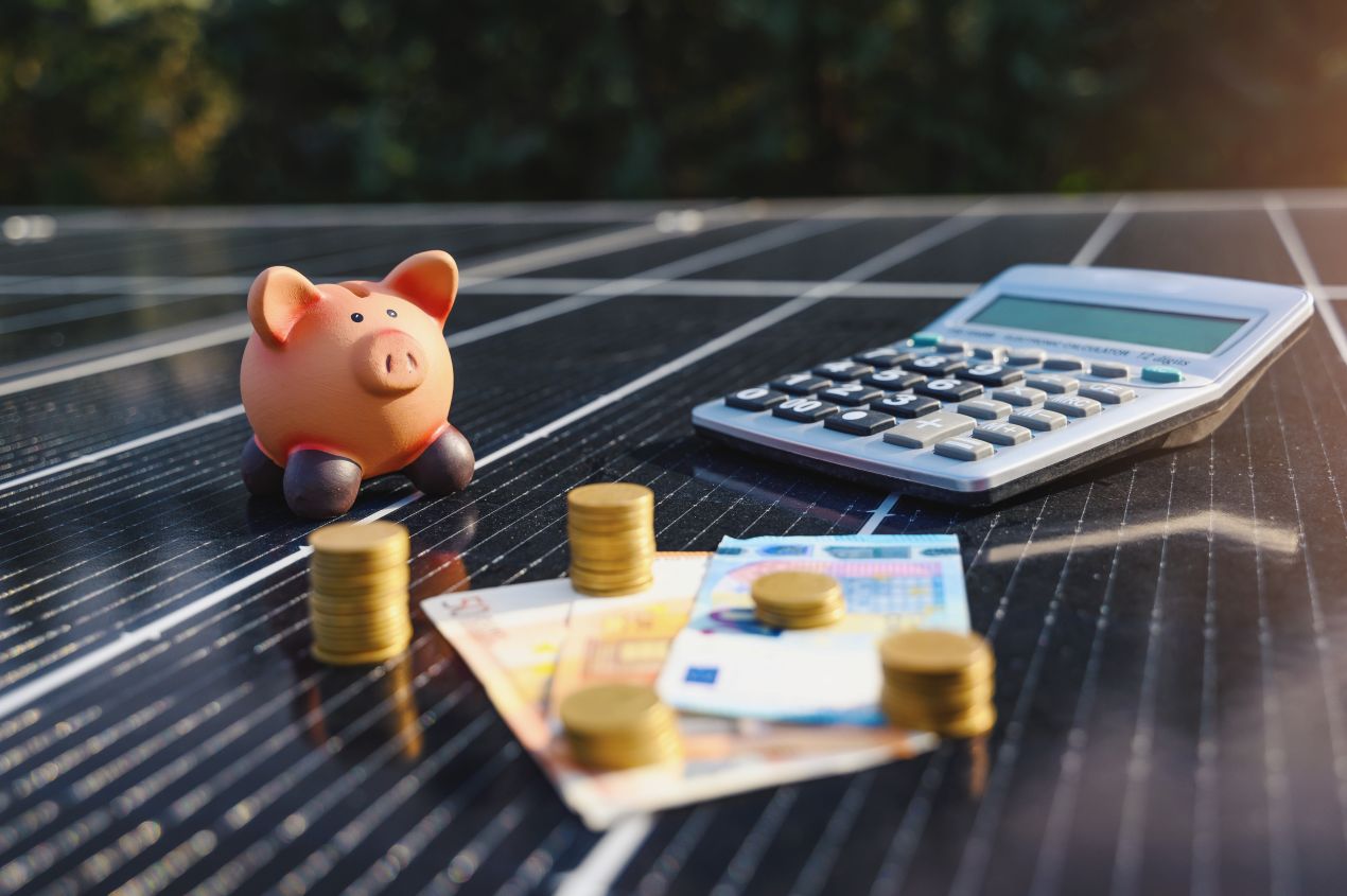 Sparschwein und Taschenrechner auf Solarpanel – Symbolbild fuer Kostensenkung mit Sunny Tripower smart energy