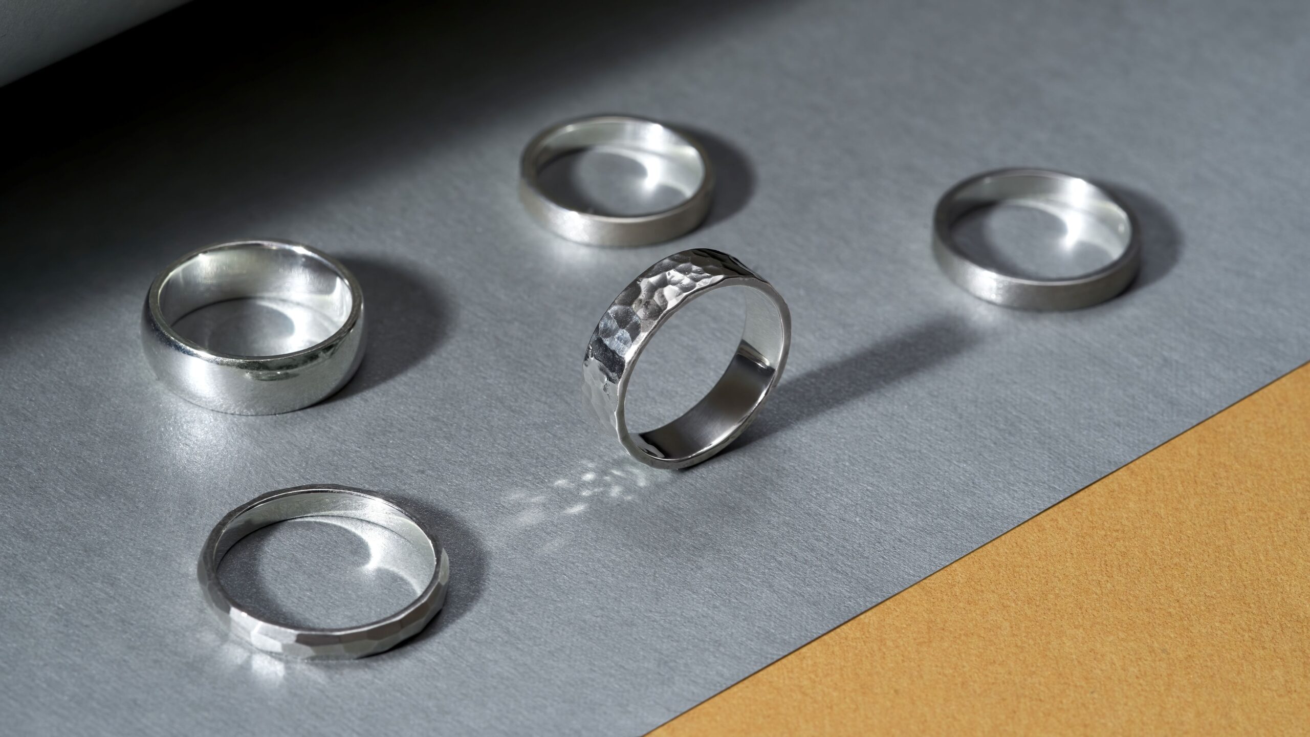 Eheringe für Männer aus Silber in verschiedenen Designs auf grauer Unterlage